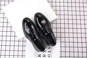 A detailed top view shot of classic black shiny leather tassel loafers for men.