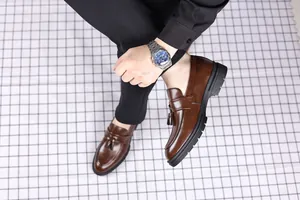 Close-up detail of men's premium brown leather tassel loafers with thick black soles
