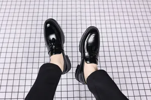 Detail of black leather tassel loafers for men on a modern grid background.