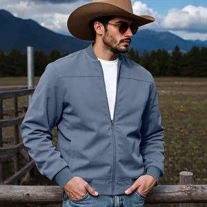 Gros plan d'un blouson d'aviateur bleu en daim pour homme dans un décor de ranch.