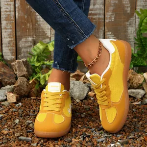 Detailaufnahme gelber Mesh-Trainer im Retrostil, getragen mit Jeans auf Kiesuntergrund
