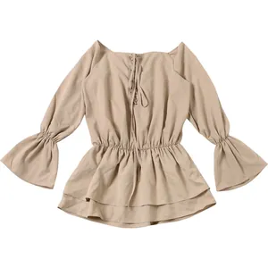 Flat lay detail of a solid beige off-the-shoulder dress with bell sleeves and lace-up.