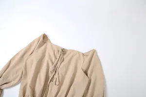 Close-up detail of beige off-the-shoulder dress with lace-up front and bell sleeves