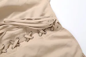 Close-up detail of beige off-the-shoulder dress featuring metallic eyelets and lace-up ties.