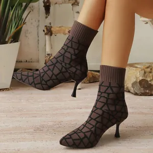 Detail view of brown knitted sock boots with black geometric patterns and thin heels.
