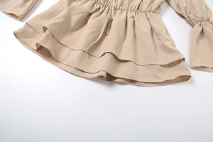 Detail of beige off-shoulder dress featuring ruffled tiered hem and elastic waist.