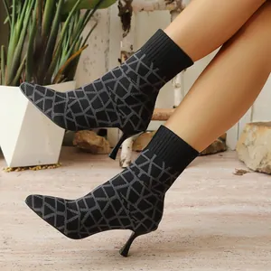 Detail of black pointed-toe stretch boots with geometric pattern and thin high heels.