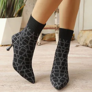 Macro view of stylish pointed-toe sock boots featuring a grey geometric knit pattern