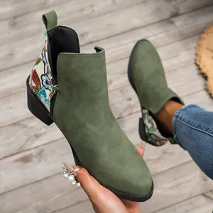 Detalle de botines western de ante verde con bordado floral y cremallera lateral.