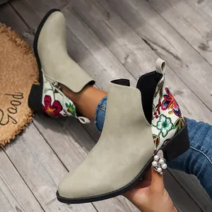 Vista detallada de botines western de ante con bordado floral vibrante y tacón ancho