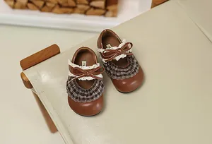Elegante braune Mädchen Mary Jane Schuhe mit Spitze und Karos auf einem weißen Stuhl