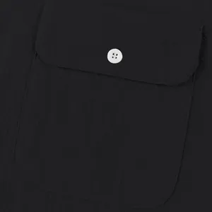 Primer plano del bolsillo de una camisa de lino negra con botón blanco en contraste