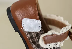 Detailaufnahme des verstellbaren Klettverschlusses mit Spitzenbesatz an Mädchenschuhen