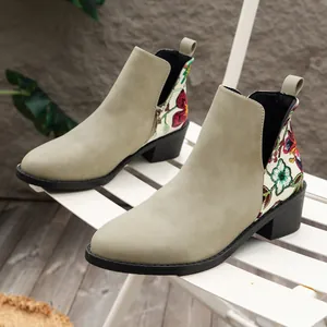 Detalle de botines de gamuza verde salvia con diseño floral colorido en el talón.
