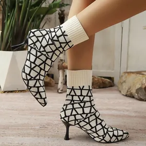 Close-up of pointed-toe sock boots with black and white geometric knit pattern and high heel.