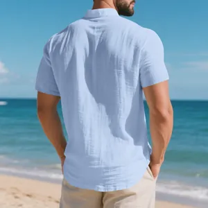 Vista trasera de una camisa de lino azul claro para hombre con cuello mandarín en la playa.
