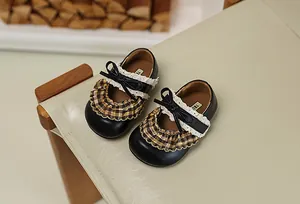 Detailansicht schwarzer Mädchen-Mary-Janes mit karierten Rüschen und feinem Spitzenbesatz.