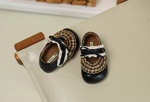 Draufsicht auf schwarze Lolita-Kinderschuhe mit karierten Rüschen und Spitzendetails