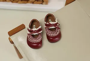 Draufsicht auf rote Prinzessinnenschuhe für Kleinkinder mit Spitze, Schleife und Rüschen