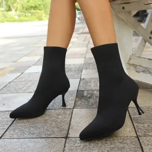 Detail view of black pointed-toe elastic sock boots with slim kitten heels worn by model