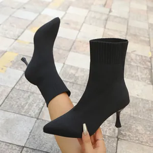 Close-up of black knitted pointed-toe sock boots featuring elegant stiletto high heels.