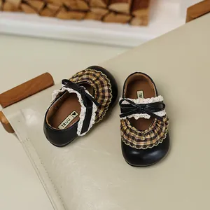 Detailansicht schwarzer Mädchen-Prinzessinnenschuhe mit Spitze und karierten Rüschen.