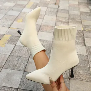 Close-up detail of beige pointed toe stretch fabric sock boots with elegant stiletto heels