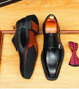 Detailed view of handmade black leather Monk strap shoes with double buckles on wood.