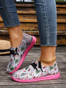 Close-up of Christmas themed graffiti canvas loafers with pink soles on model's feet