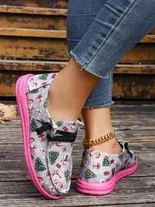 Close-up of women's Christmas print canvas shoes with pink soles and black laces.