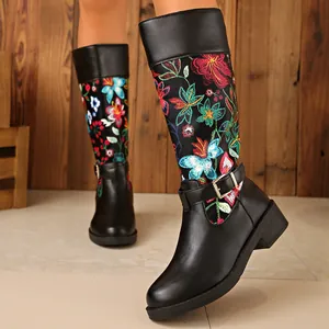 Detail view of black leather boots with colorful floral embroidery and buckle strap