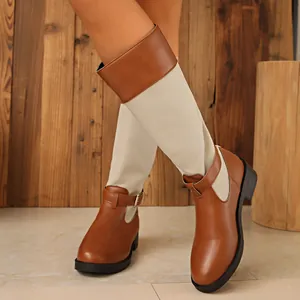 Detail of two-tone knee-high boots with brown leather and beige canvas textures.
