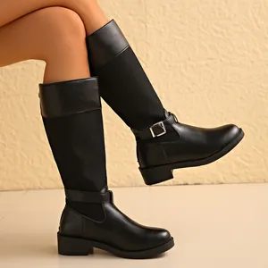 Close-up detail of black knee-high boots featuring patchwork fabric and ankle buckle strap