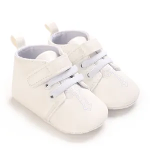 Detail view of white infant baptism shoes featuring delicate cross embroidery design