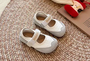 Detailaufnahme der cremefarbenen und grauen Mary Jane Sneaker für Mädchen auf Matte