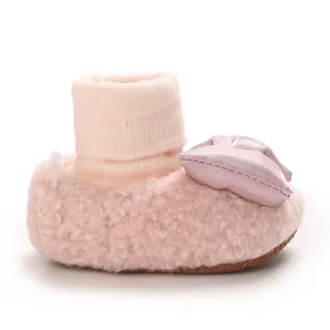 Close-up of pink plush baby walker shoes with satin bow detail and ribbed ankle cuff.