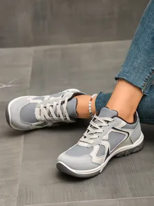 Nahaufnahme von grauen Retro-Sneakern in Kontrastfarben, getragen mit Jeans