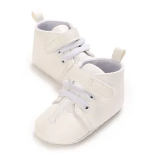 Close-up detail of white baby baptism shoes featuring an embroidered cross and velcro strap