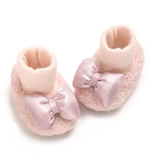 Detail of soft pink baby booties with satin bow and elastic ribbed ankle cuff