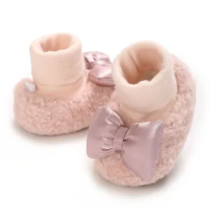 Detailed close-up view of pink fuzzy baby booties featuring elegant satin ribbon bows.