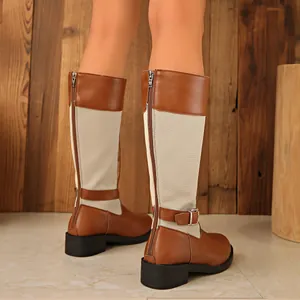 Detail view of brown and beige patchwork knee-high boots with buckle and zipper.