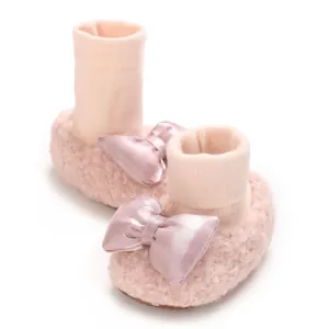 Detailed view of pink fleece baby sock shoes with satin bows for winter warmth