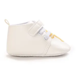 Detail view of cream baptism baby shoe with golden cross embroidery and velcro strap