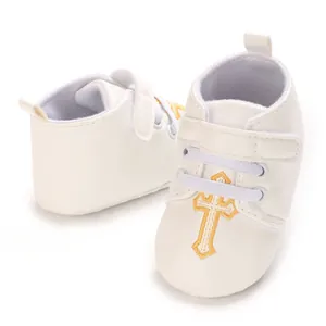 White baby baptism shoes featuring a golden embroidered cross and convenient velcro strap