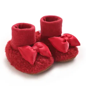 Detailed view of red fleece baby girl booties with large satin bow decoration