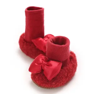Detailed close-up of red fleece-lined baby walking shoes with large decorative satin bows
