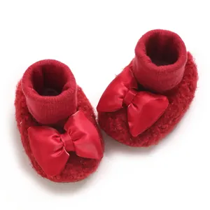 Close-up detail of soft red fleece baby walker shoes with large decorative satin bows