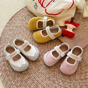 Drei Paar weiche Mary-Jane-Sneaker für Mädchen in Gelb, Grau und Rosa auf Strohmatte