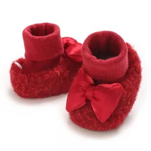 Cozy red plush baby booties featuring a large decorative satin bow for infant girls