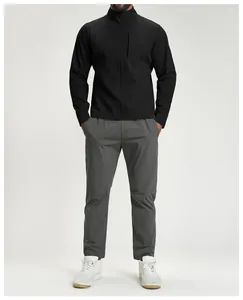 Vista frontale giacca tecnica nera da uomo con collo alto e pantaloni outdoor grigi